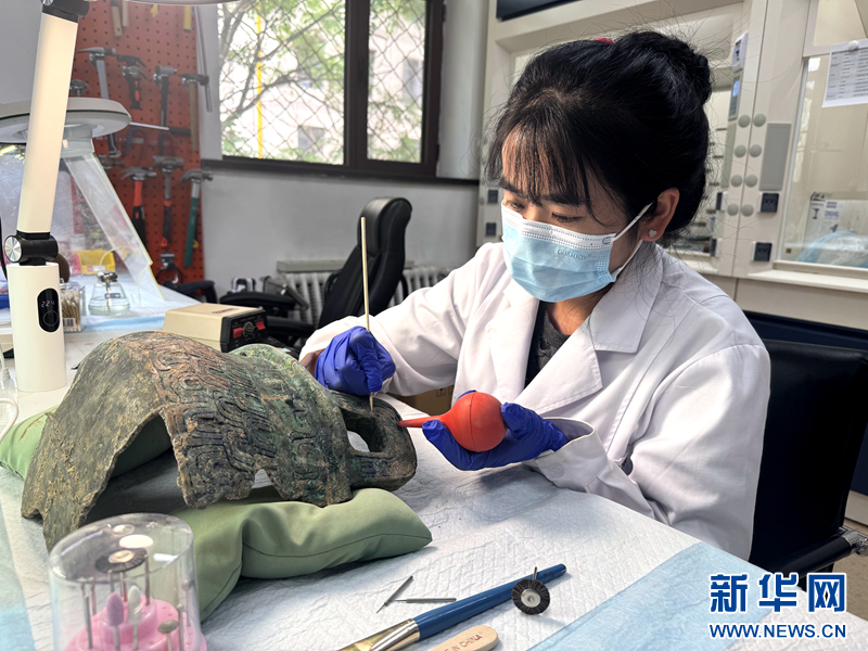 6月6日，在甘肃省博物馆文物保护修复中心，工作人员正在清除铜鼎表面硬结物。新华网发（刘欣瑜　摄）