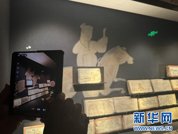 6月6日，在甘肃省博物馆内的丝绸之路文明展厅，观众拍照记录“驿使图”画像砖（复制品）。新华网发（刘欣瑜　摄）