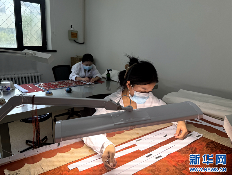 6月6日，在甘肃省博物馆文物保护修复中心，工作人员正在平整革命文物锦旗。新华网发（刘欣瑜　摄）