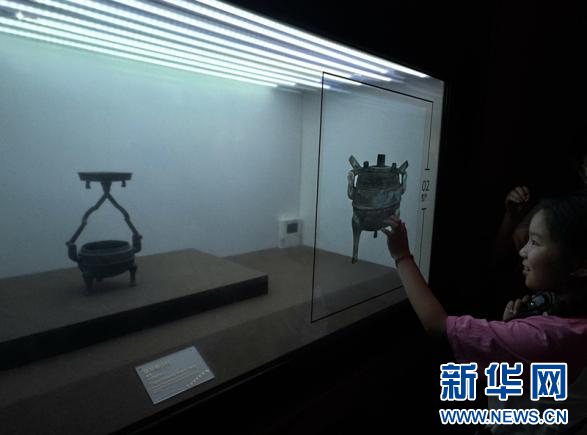 6月6日，在甘肃省博物馆内的丝绸之路文明展厅，小朋友在电子屏幕上体验鼎形铜行灯的使用方法。新华网发（刘欣瑜　摄）