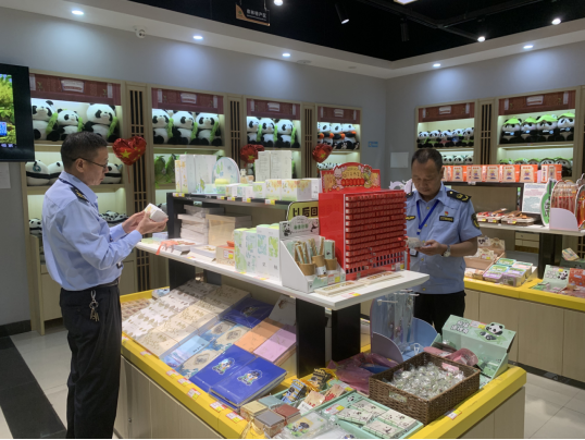 执法人员在景区商户检查商品标签标识，右为周立志。