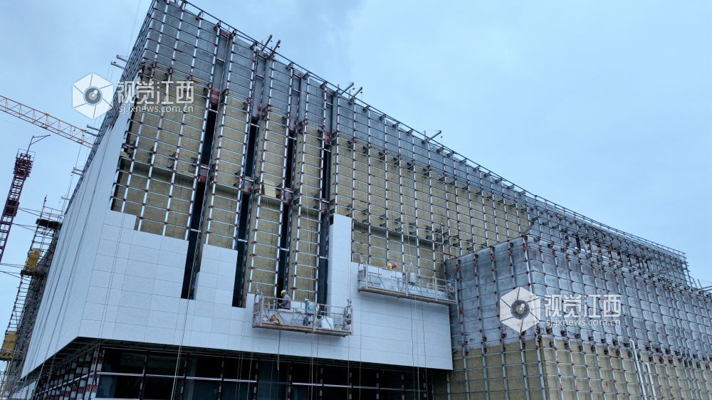 2025年6月5日,江西省遂川县文化产业中心项目施工进入竣工冲刺阶段,建筑工人正利用晴好天气抓紧幕墙等分项工程的建设。
