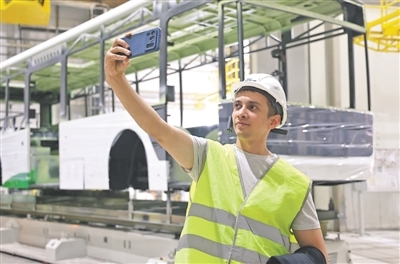 塔吉克斯坦记者与工厂生产线上的客车车身合影。本报记者 张志文摄