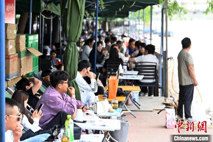 5月31日，甘肃兰州，民众在黄河岸边的茶摊喝茶。端午假期首日，众多游客选择在黄河兰州段的茶摊喝茶，乘坐羊皮筏子、快艇游览黄河。中新社记者　九美旦增　摄