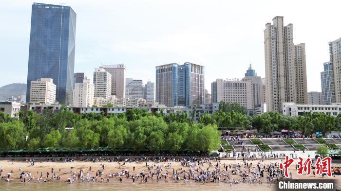 5月31日，甘肃兰州，民众在黄河岸边休闲游玩。端午假期首日，众多游客选择在黄河兰州段的茶摊喝茶，乘坐羊皮筏子、快艇游览黄河。（无人机照片）中新社记者　九美旦增　摄