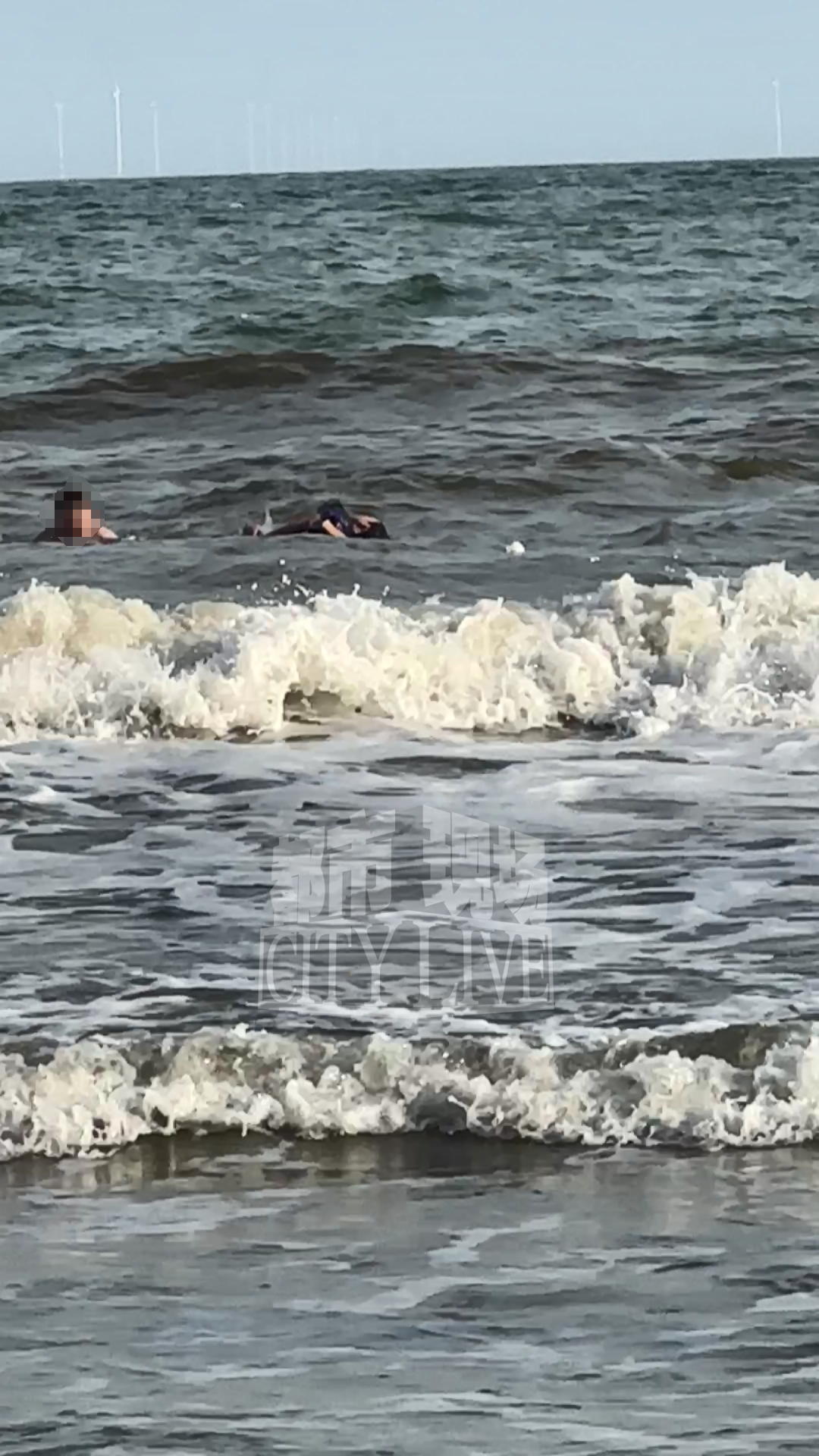 (事发时视频截图,陈强在海浪中托起溺水男孩)