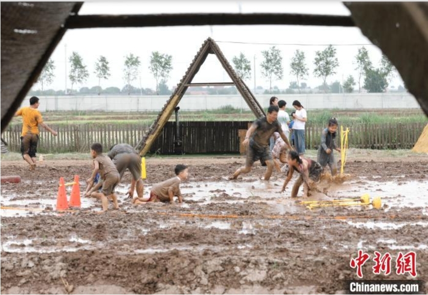 稻田寻宝、牧场奇遇、插秧比赛……端午节当天，在河北省沧县兴济镇南堤村盐碱稻田乐园里，200多个家庭参与“盐碱稻田寻宝季”活动，感受别样端午。图为游客在河北省沧县兴济镇南堤村的盐碱稻田乐园中体验泥巴作战。 田博 摄