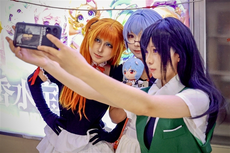 年轻的二次元爱好者聚集在谷子店铺附近，精心装扮成各自喜爱的角色，打卡拍照。