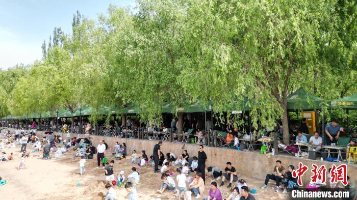 5月31日，甘肃兰州，民众在黄河岸边的茶摊喝茶。端午假期首日，众多游客选择在黄河兰州段的茶摊喝茶，乘坐羊皮筏子、快艇游览黄河。（无人机照片）中新社记者　九美旦增　摄