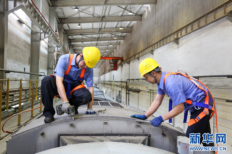 5月30日,在检修库内,车辆电工正在进行客车空调顶盖拆卸作业。新华网发(程锦龙 摄)