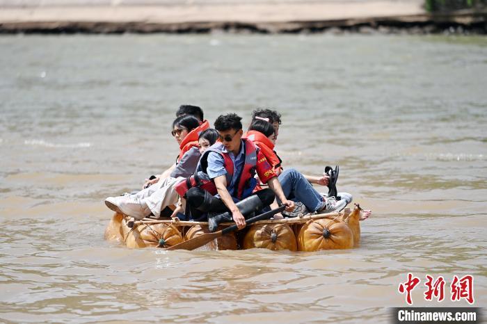 5月31日，甘肃兰州，游客乘坐羊皮筏子游览黄河。端午假期首日，众多游客选择在黄河兰州段的茶摊喝茶，乘坐羊皮筏子、快艇游览黄河。中新社记者　九美旦增　摄