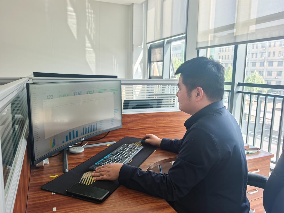 工业互联网运维员孙奇才在看企业报表，分析企业运营管理数据。