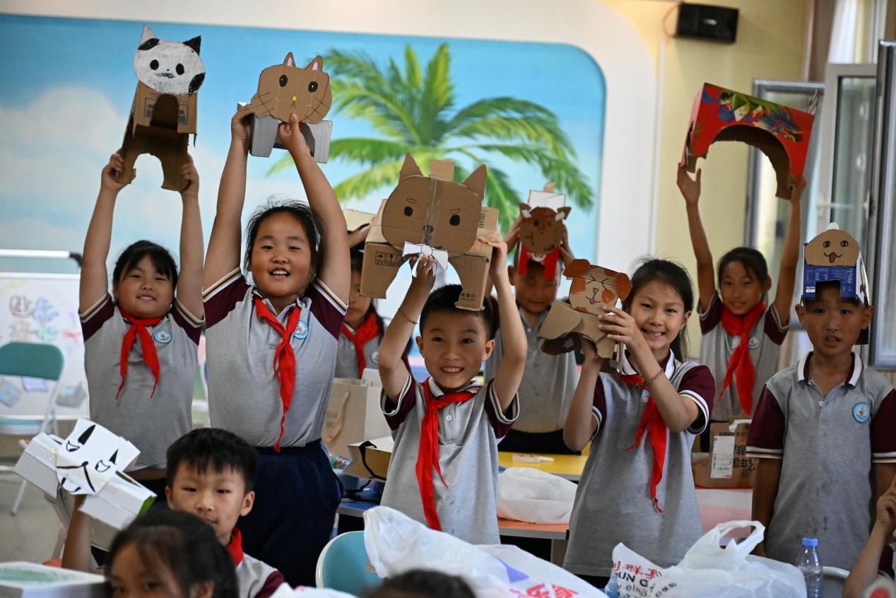 6月3日，山东省青岛市即墨区德馨小学东部分校的学生展示利用废旧纸壳制作的玩具。