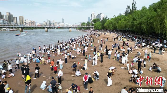 5月31日，甘肃兰州，民众在黄河岸边休闲游玩。端午假期首日，众多游客选择在黄河兰州段的茶摊喝茶，乘坐羊皮筏子、快艇游览黄河。（无人机照片）中新社记者　九美旦增　摄