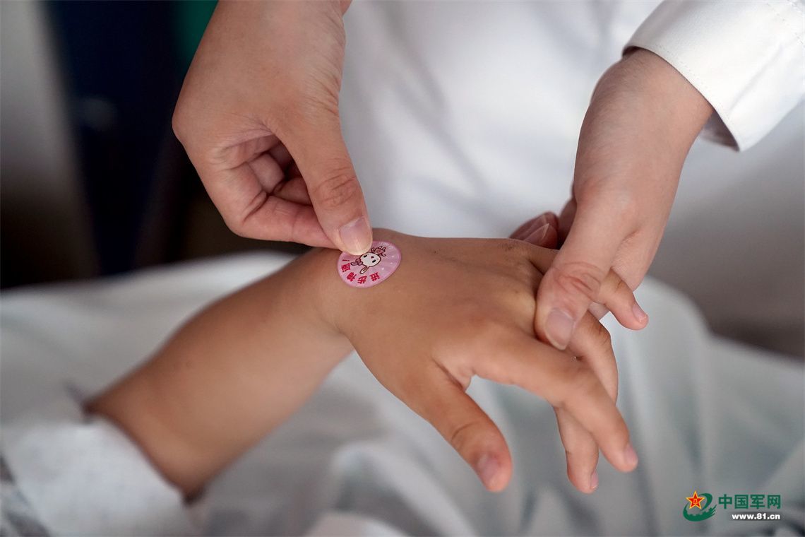 护士把“勋章贴纸”贴在军娃小宇手上。中国军网记者孙悦 摄