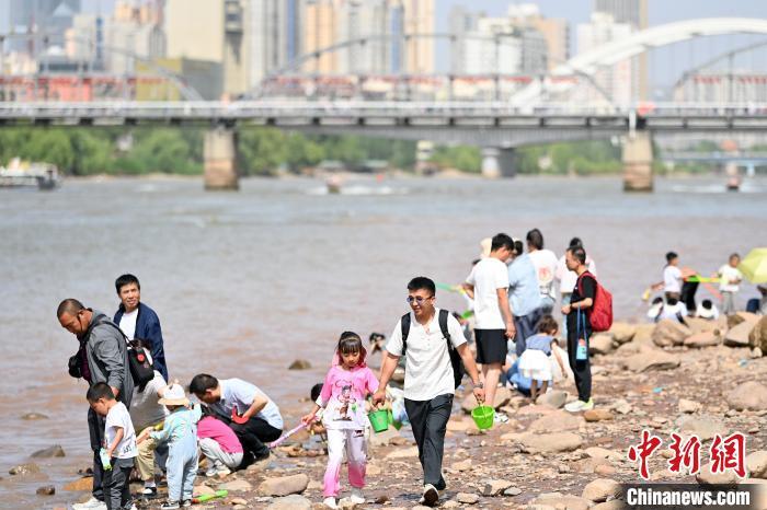 5月31日，甘肃兰州，民众在黄河岸边休闲游玩。端午假期首日，众多游客选择在黄河兰州段的茶摊喝茶，乘坐羊皮筏子、快艇游览黄河。中新社记者　九美旦增　摄