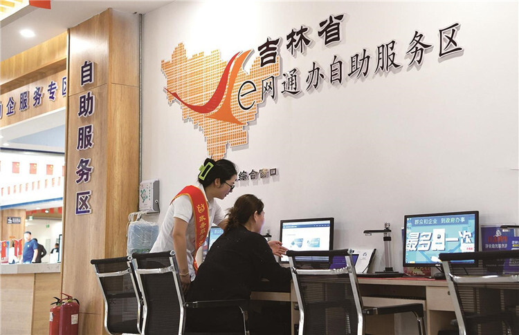 工作人员协助群众在e网通办服务区自助办件。