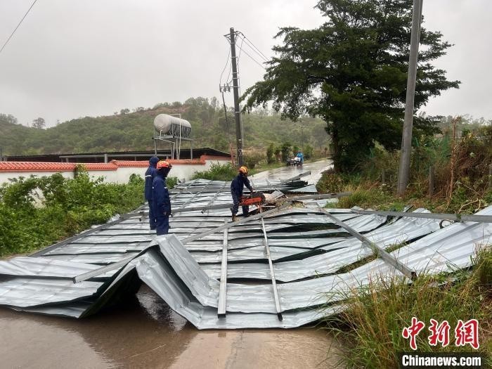 6月13日，台风“蝴蝶”将乐东黎族自治县九所镇一座铁皮房屋顶掀翻吹落，阻挡附近道路，消防救援人员处置险情。乐东消防救援大队 供图