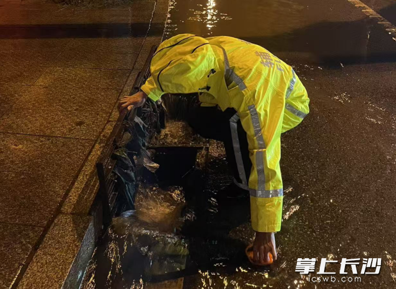 民警清理下水道附近树叶、垃圾等,并打开下水道井盖加速排水。长沙晚报通讯员 杨哲 供图