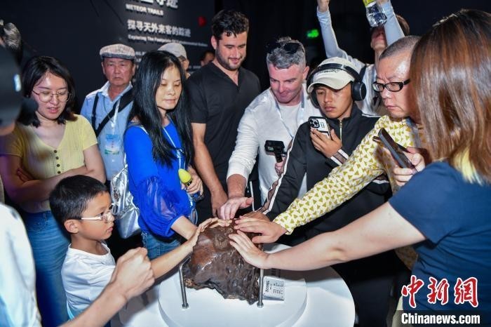 6月10日，游客在文昌极星陨石博物馆触摸感知陨石标本。中新网记者 骆云飞 摄
