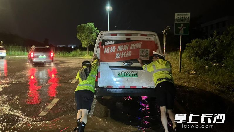 雨幕中,执勤交警带队民警挽起裤腿,弓着身子,在积水中奋力推车。长沙晚报通讯员 杨哲 供图