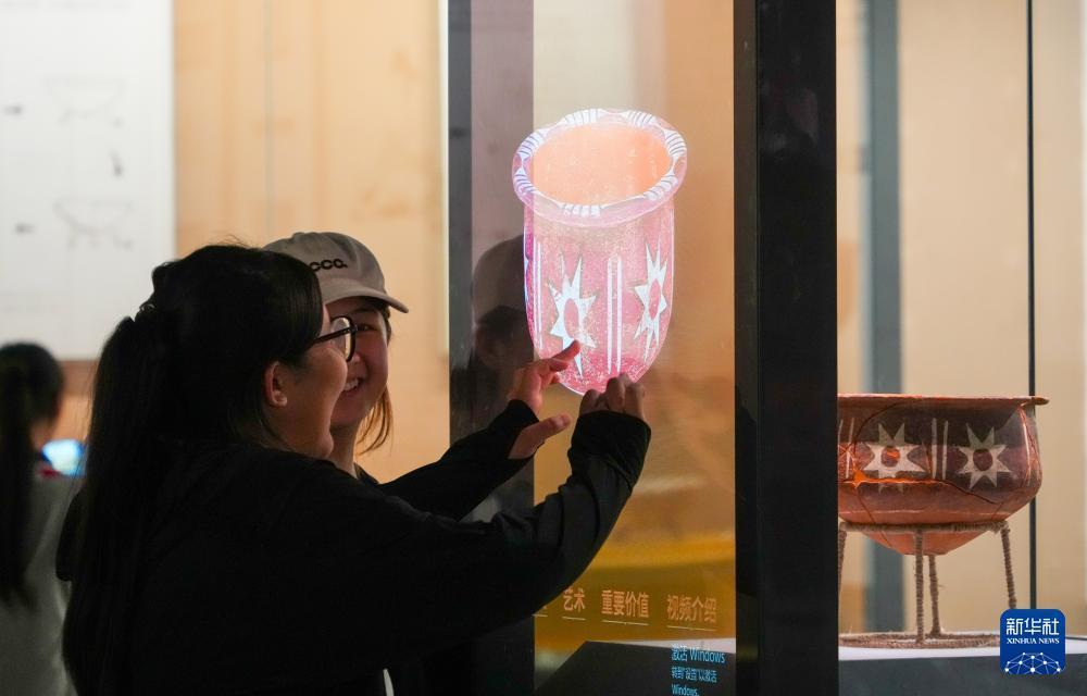 人们在大汶口遗址博物馆通过多媒体设备多角度观看大汶口遗址出土的八角星纹彩陶豆