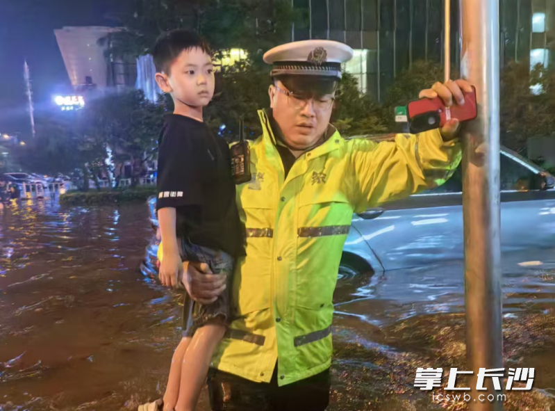 开福交警小心地将孩子抱离地面,踩着积水中的安全路线稳步走向马路对面。长沙晚报通讯员 杨哲 供图
