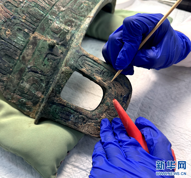 6月6日，在甘肃省博物馆文物保护修复中心，工作人员正在清除铜鼎表面硬结物。新华网发（刘欣瑜 摄）