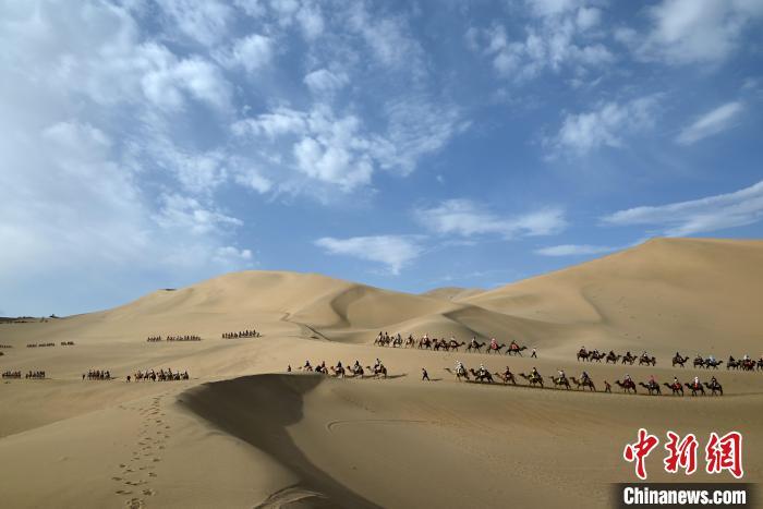 6月7日，游客骑骆驼在敦煌市鸣沙山月牙泉景区游览。张晓亮　摄