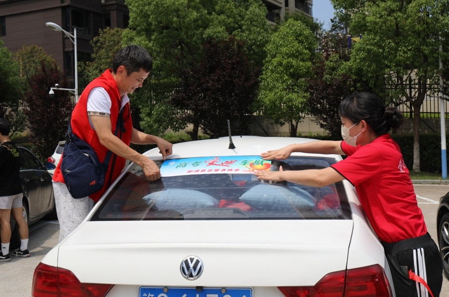 江西九江市彭泽县爱心送考志愿活动现场，爱心车主们正在给自家车贴爱心标识及系绿丝带。（金书斐 摄）