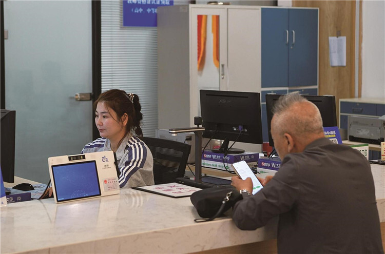 群众在工作人员指导下通过手机自助办件。