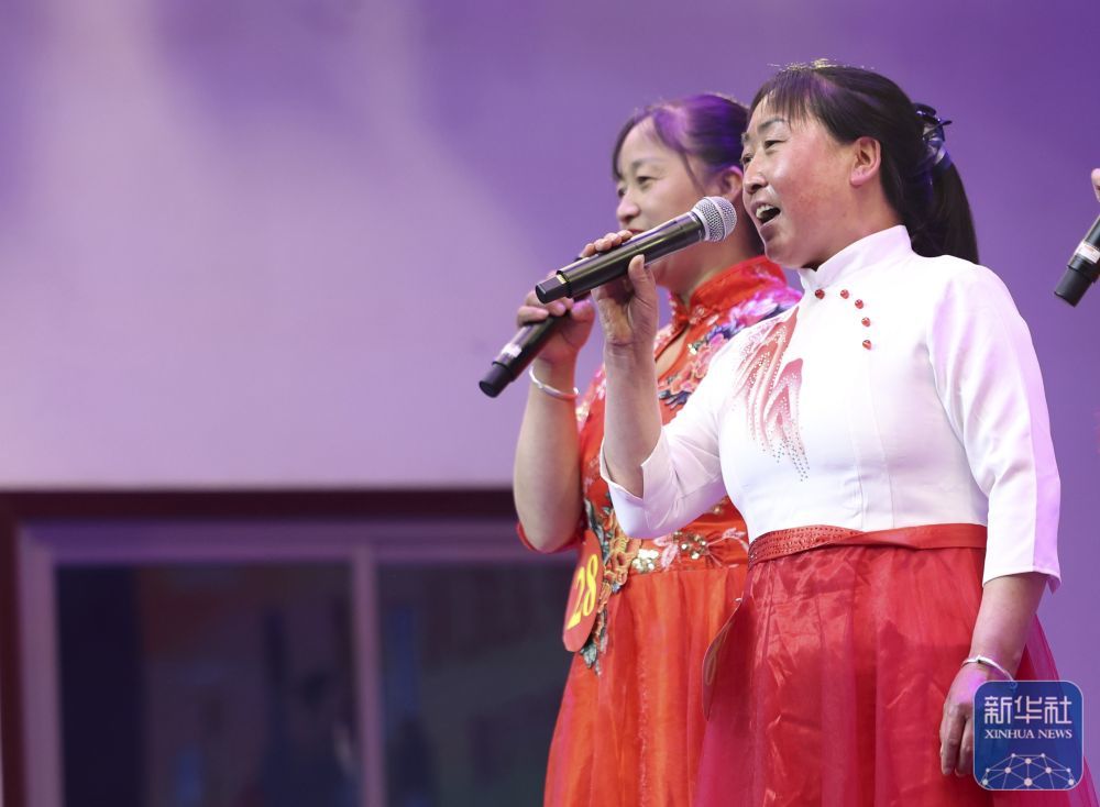 6月11日，在甘肃省定西市岷县举行的第二十五届洮岷“花儿”歌手大赛上，参赛选手刘巧英（右）在进行表演。