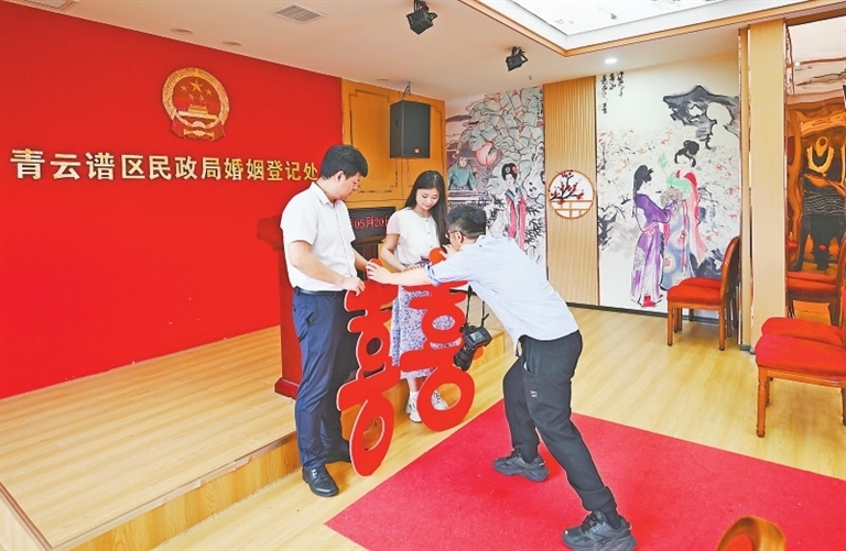 领证跟拍师陈清源为新人送上“囍”字道具，让拍摄的照片更有喜庆氛围。