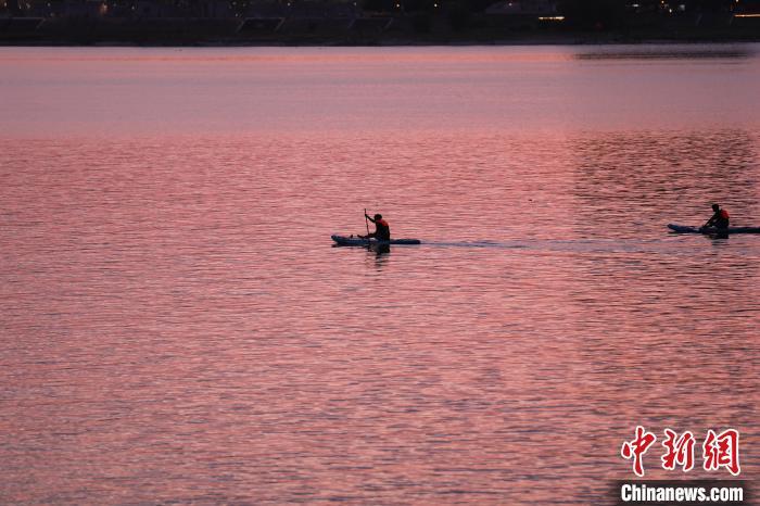 6月16日傍晚，江西南昌上空落日美景，晚霞满天，市民滑浆板于赣江上欣赏美丽晚霞。中新社记者 刘思伟 摄