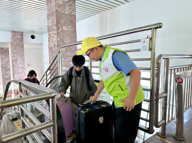 新余站志愿者帮助旅客提拿行李。（桓玉和 摄）