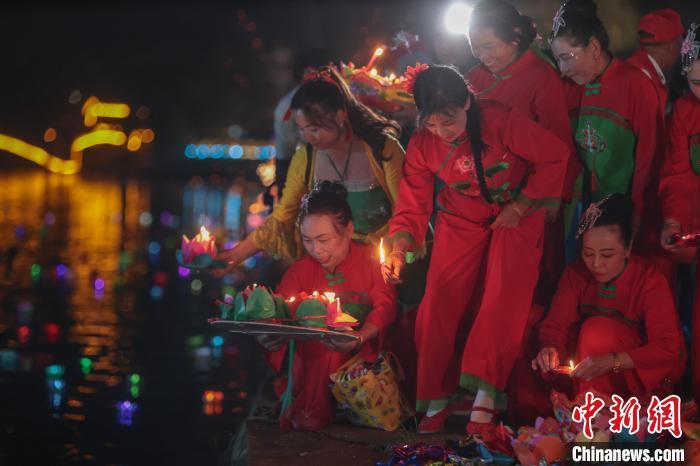 图为在江西省瑞昌市范镇河灯节现场，民众将一盏盏点燃的河灯放入水中。　刘力鑫 摄