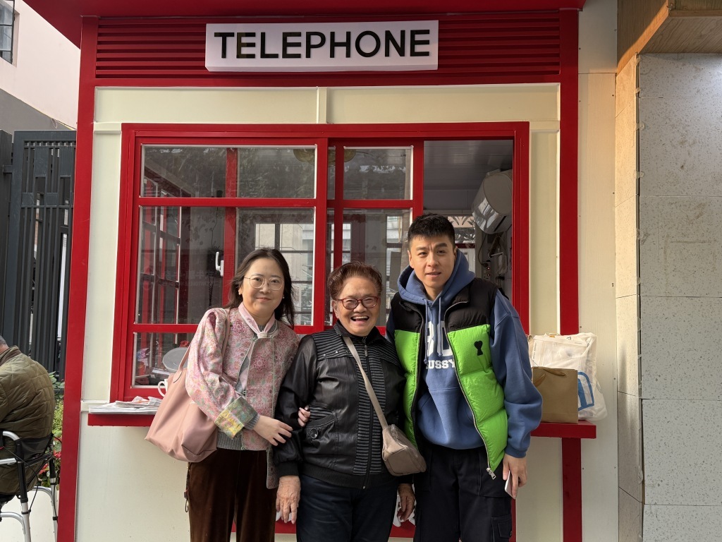 公用传呼电话亭改造后，沈阿姨和编剧杜竹敏和导演申俊磬合影