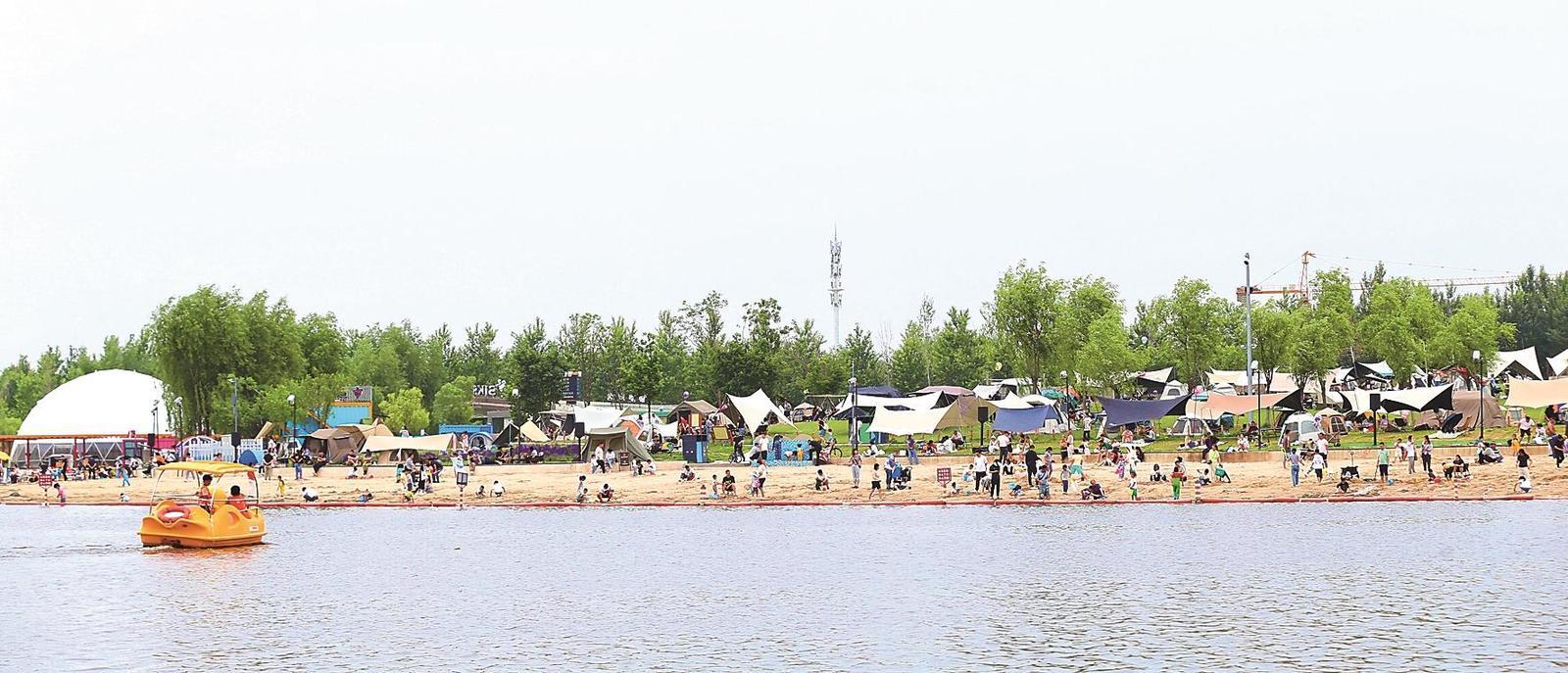 市民在长春市南溪湿地公园露营、戏水。