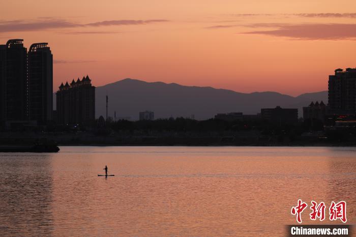 6月16日傍晚，江西南昌上空落日美景，晚霞满天，市民滑浆板于赣江上欣赏美丽晚霞。中新社记者 刘思伟 摄