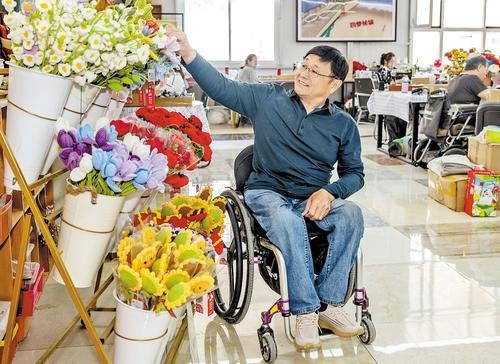 6月9日，罗东升在秦皇岛市残疾人创业就业基地查看大家做的手工。 本报记者 赵杰摄