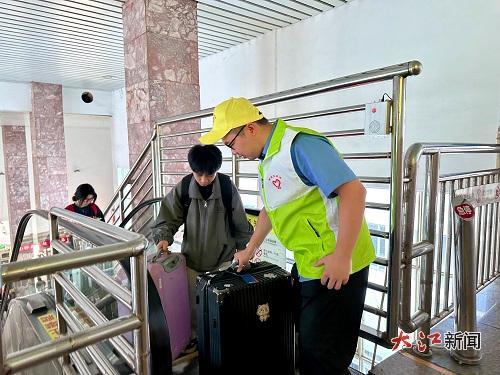 新余站志愿者帮助旅客提拿行李。（桓玉和摄）