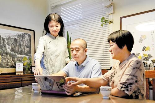 6月14日，赵天翼（左）一家在家中翻阅老相册，重温家族红色记忆。 本报记者 许佳奇摄