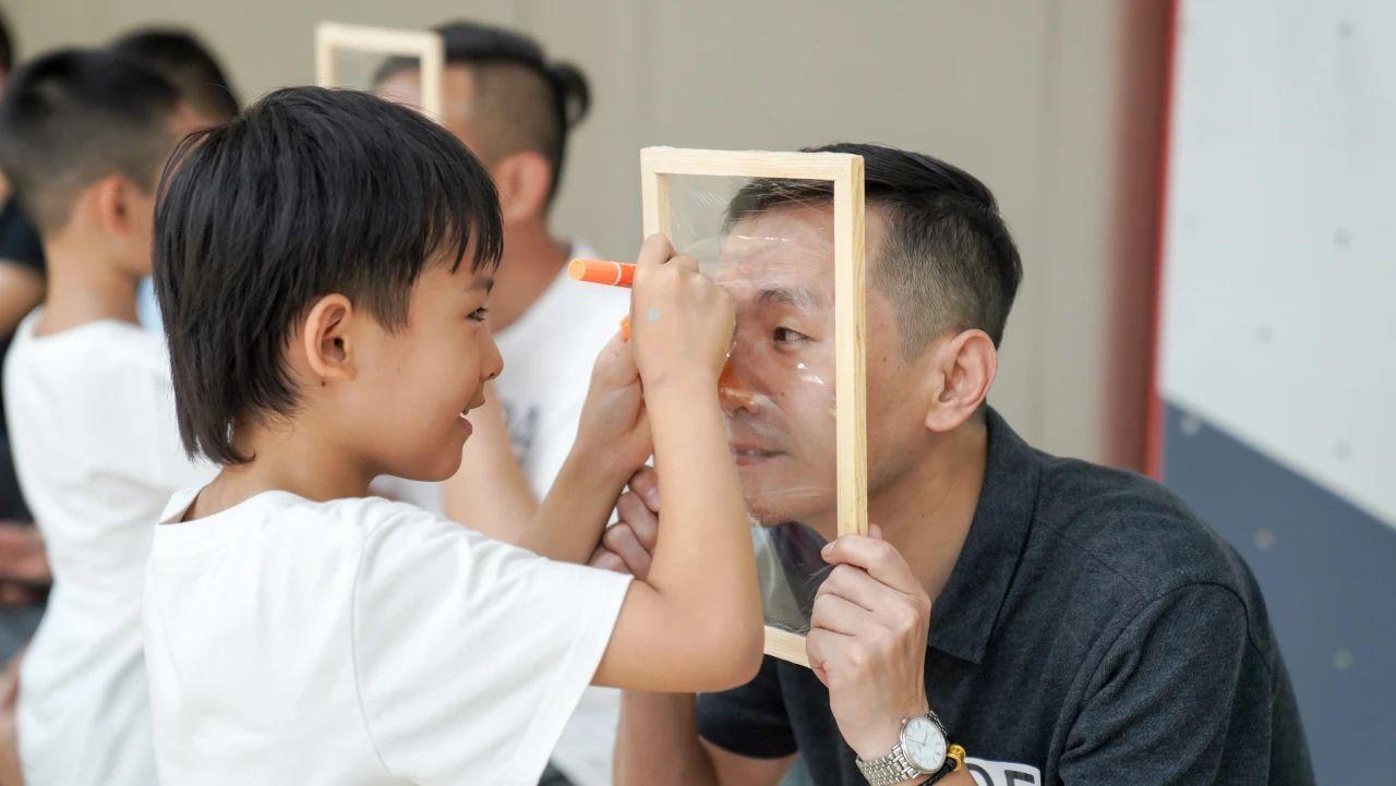 孩子们在塑封相框上,一笔一画,专注描绘心中爸爸的模样。