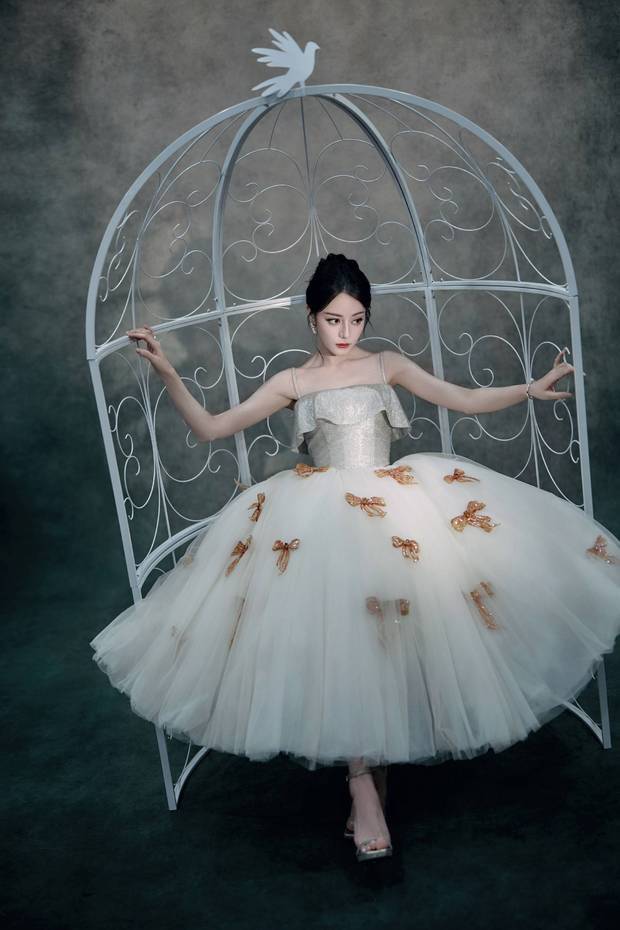 搜狐娱乐讯 17日，迪丽热巴最新的写真美照释出，她身着蝴蝶结白纱裙，宛若被困在鸽子笼子里的优雅美人！