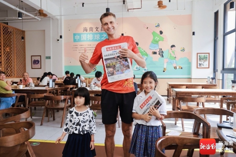 海南旅游国际推荐官购买报纸，与《南国都市报》报童合影留念。主办方供图