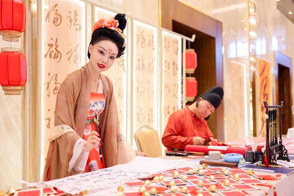 “新华·长安之夜”文化交流活动现场的丝路文化市集上,演员在展示书法艺术。