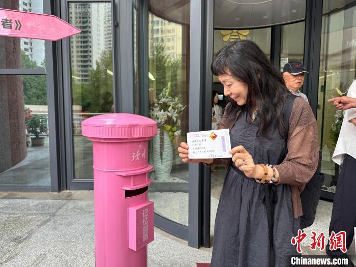 图为台湾作家宇文正，往“读者记忆邮筒”中投递明信片。闫姣　摄