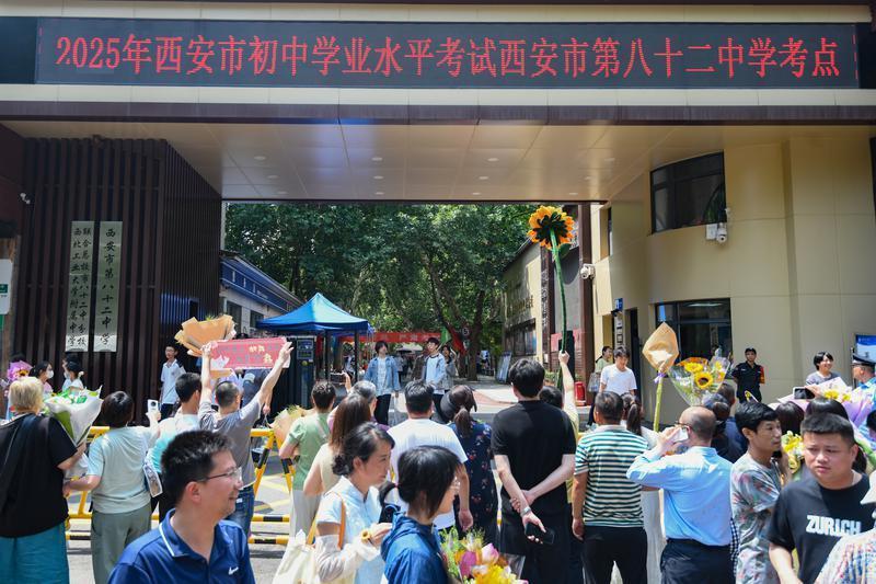 在西安市第八十二中学考点，家长高举向日葵等待考生。记者 郝钟毓 实习生 郝雨辰一摄