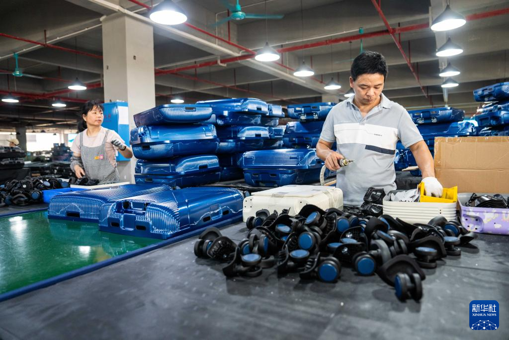 6月23日，在蓝山县皮具箱包科技产业园一家箱包生产企业，工人在安装拉杆行李箱滚轮。