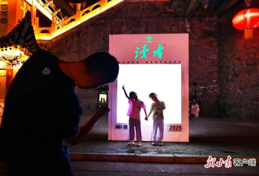 家长为孩子在《读者》灯牌前拍照 新甘肃·甘肃日报记者 马伊星